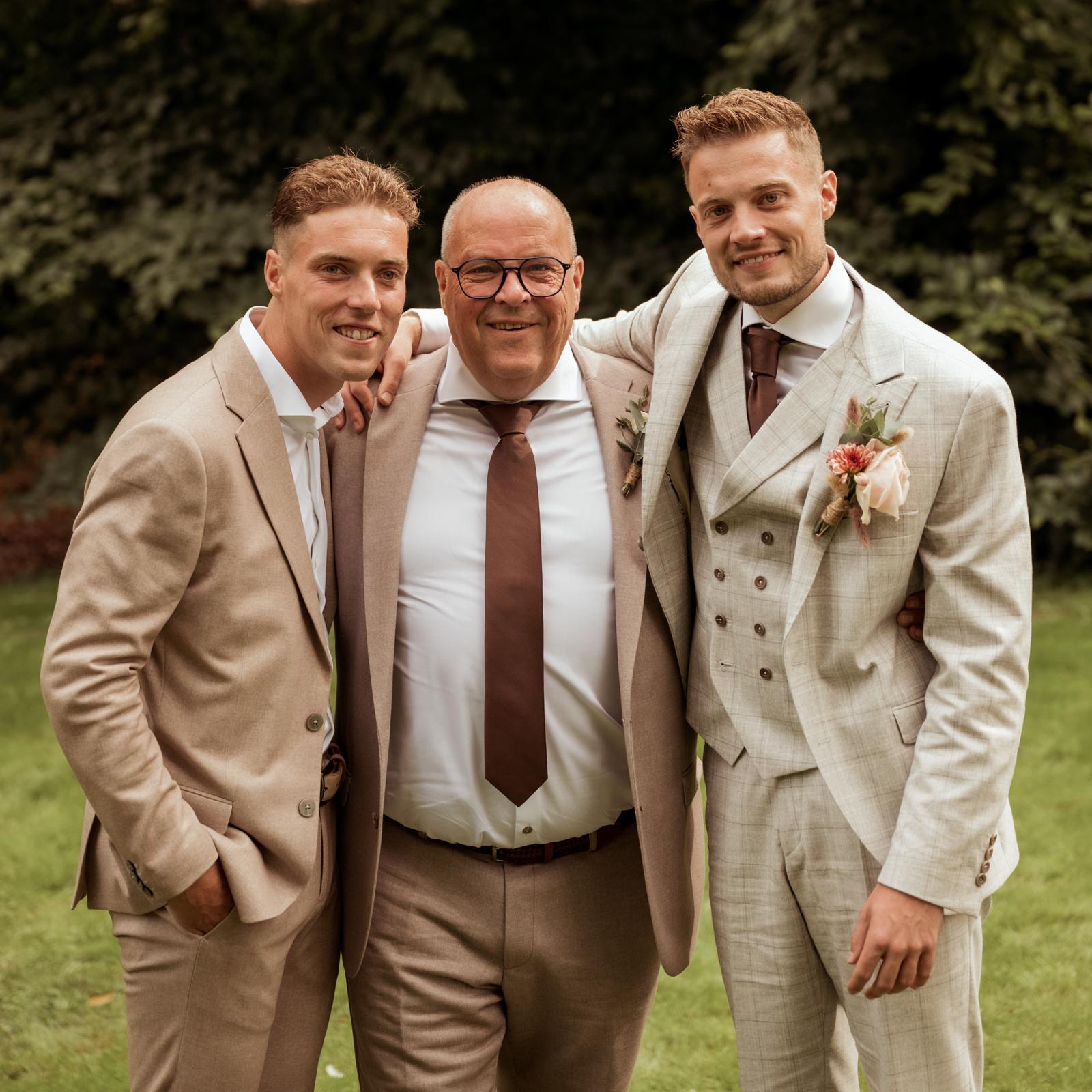 Bruidegom met getuigen en familie in stijlvolle trouwoutfits